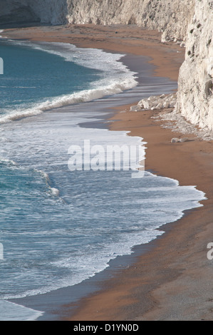 Der Strand und brechen Surfen unterhalb der Kreidefelsen kratzig unten, Durdle Door, Dorset, England, UK. Stockfoto