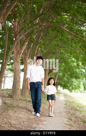 ein Vater und eine Tochter, ein Spaziergang entlang der Bäume Stockfoto