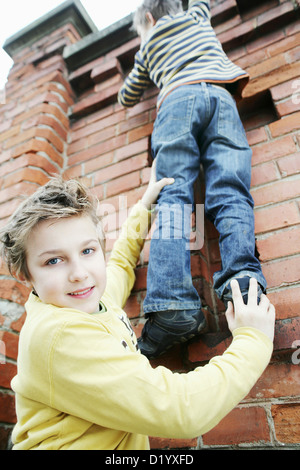 Junge, Freund eines Bunk-up über eine Wand Stockfoto