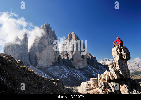 Frau sitzt auf einem Felsenturm vor den drei Zinnen, Tre Cime di Lavaredo, Sextener Dolomiten, Dolomiten, UNESCO-Welt-gen Stockfoto