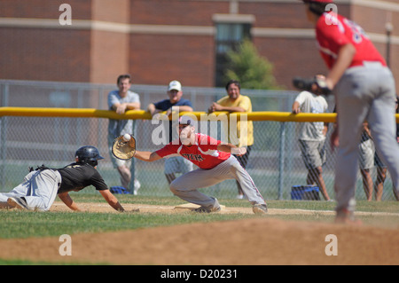 Runner taucht zurück in die Tasche, als der erste Baseman einen Pick-off-Wurf aus seinem Krug greift. USA. Stockfoto