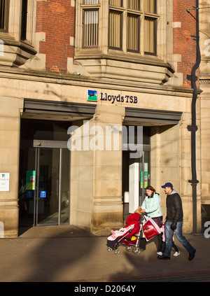 Ein junges Paar mit einem Baby gehen vorbei an Lloyds TSB Bank in Church Street nr High Street Sheffield England Stockfoto