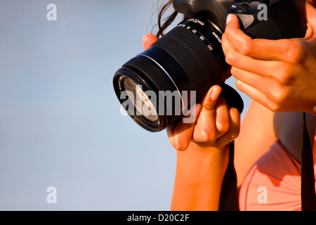 Ein Mädchen-Hände halten eine DSLR-Kamera, wie sie konzentriert ist, um ein Foto von etwas machen in der Nähe der Erde. Stockfoto