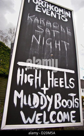 'Welcome' high Heels und Muddy Boots und Karaoke unterzeichnen vor einem Pub in Essex, England Stockfoto