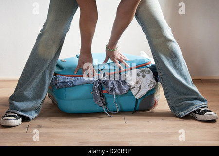 Frau versucht, ihren Koffer zu schließen Stockfoto