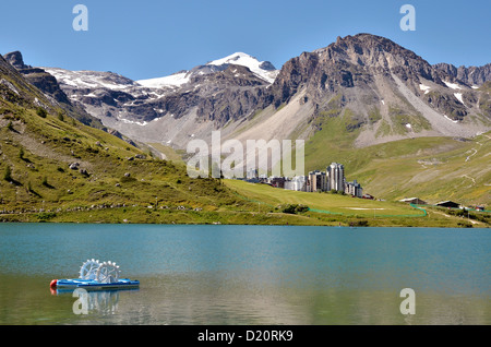 See von Tignes mit Tretboot und Tignes Val Claret Dorf im Hintergrund. Tignes ist eine Gemeinde in der Tarentaise-Tal, Frankreich Stockfoto