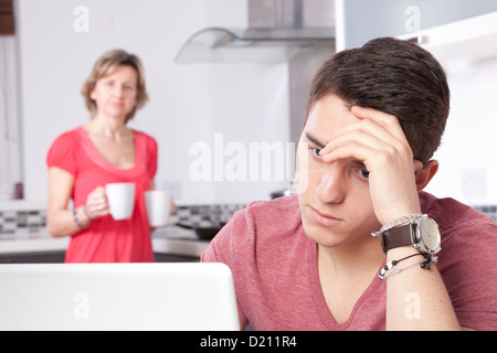 Worri Mann mit einem digitalen Tablet-Bildschirm oder Monitor zu betrachten. In einer modernen Küche sieht eine Frau mit 2 Tassen Buchungsänderungen Stockfoto