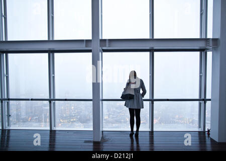 Der Blick von der Shard, London, UK. 10.01.2013 Bild zeigt eine Frau mit Blick vom The View from The Shard auf der 72. Etage mit Blick auf eine graue Nebel Skyline über die City of London, England, Vereinigtes Königreich.   Bildnachweis: Jeff Gilbert / Alamy Live News Stockfoto