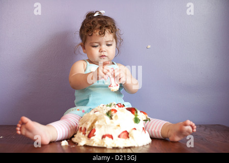 Niedlichen Mädchen spielen mit einem Geburtstagskuchen und Nummer eins Kerze. Stockfoto
