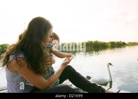 Junge Mutter und Tochter sitzen auf einem hölzernen Steg, alte Donau, Wien, Österreich Stockfoto