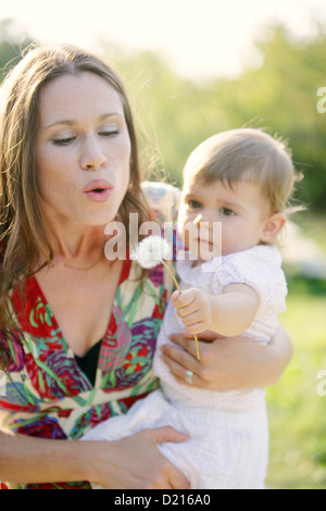 Junge Mutter mit ihrer Tochter bläst eine Löwenzahn-Uhr, alte Donau, Wien, Österreich Stockfoto