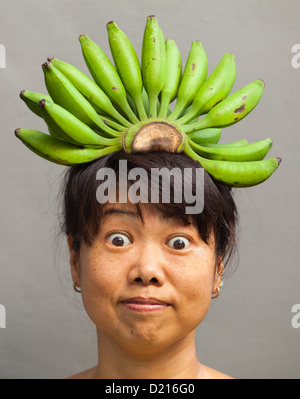 Glückliche und gesunde Frau mit Banane Krone auf dem Kopf Stockfoto