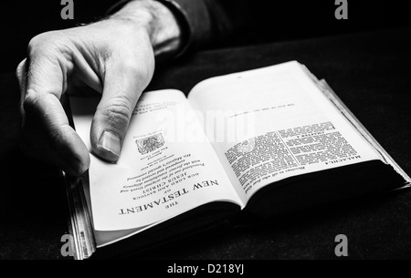 Ein Mann liest die Bibel mit einer Hand. Stockfoto