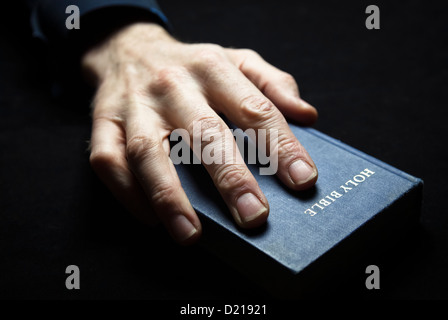 A mans Hand hält die Heilige Bibel. Stockfoto