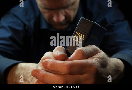 Das Bild von einem Mann, der betet, hält eine Bibel. Stockfoto