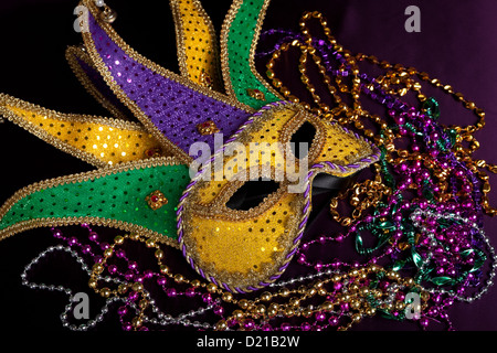 Ein Karneval Narr Maske mit lila, gold und grün Perlen auf schwarzem Hintergrund Stockfoto