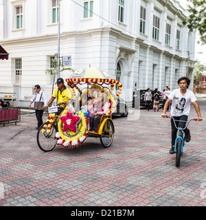 Touristen auf Rikscha-Fahrt in Melaka, Malaysia, sind eine beliebte Touristenattraktion Stockfoto