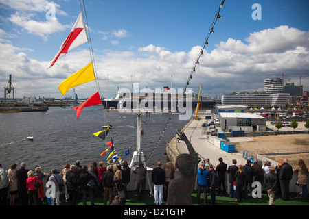 Passagiere an Bord Kreuzfahrtschiff MS Deutschland begrüßen die Ankunft des Kreuzfahrtschiffes Queen Mary 2 in Hamburg Cruise Center als par Stockfoto