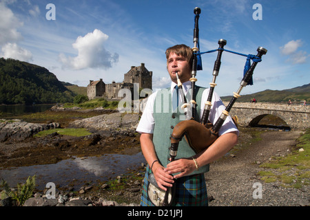 Jungen Dudelsackspieler vor Eilean Donan Castle am Loch Duich in der Nähe von Dornie, Highland, Schottland, Vereinigtes Königreich Stockfoto