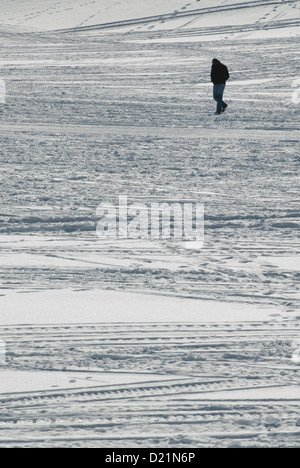 Mann zu Fuß in ein Feld bedeckt mit Schnee Stockfoto