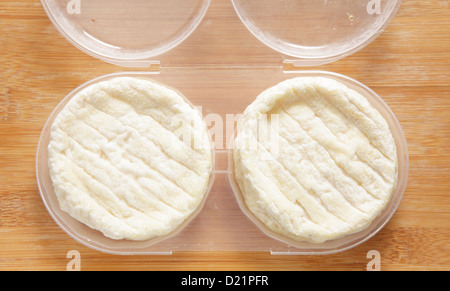 Zwei Runden der französischen Saint-Marcellin Käse in einem Container auf einer Käseplatte. Stockfoto