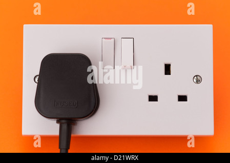 Eine UK Twin elektrische Wand-Steckdose mit einem schwarzen Stecker eingesteckt in eine der Buchsen - Studio gedreht Stockfoto