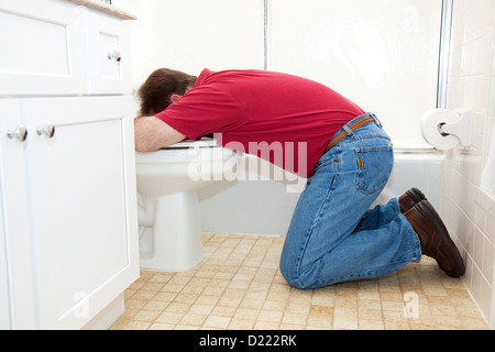 Mann auf den Knien in das Badezimmer, Erbrechen in die Toilette. Stockfoto