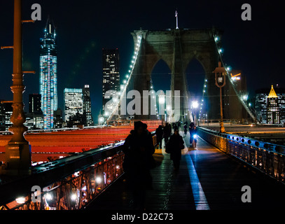 Brooklyn Bridge Manhattan dahinter, nachts beleuchtet mit Fußgängern, Rad- und über. Stockfoto