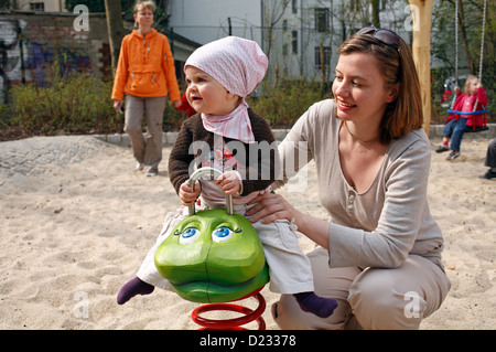 Berlin, Deutschland, ein kleines Mädchen sitzt auf einem schaukelnden Tier Stockfoto