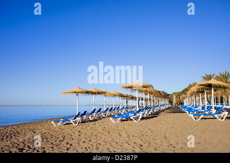 Liegestühle auf einer ruhigen Strand in der beliebten Resort Stadt Marbella in Spanien, Costa del Sol, Provinz Malaga. Stockfoto