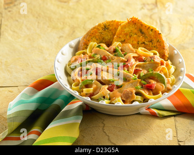 Chicken Pasta in einer cremigen Sauce serviert mit Knoblauchbrot Stockfoto