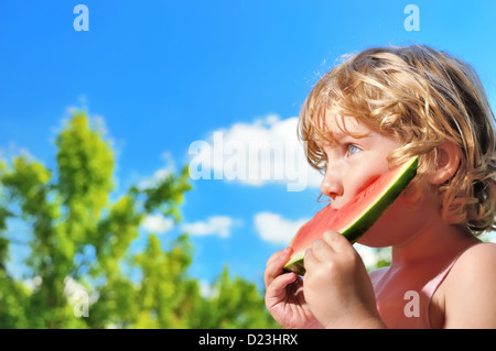 Kleine Mädchen essen Wassermelone auf den blauen Himmel. Stockfoto