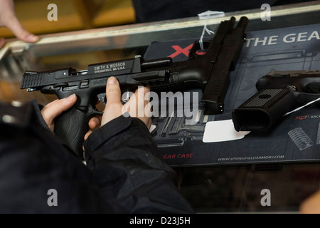 Ein Kunde interagiert mit einer Pistole auf einen Waffenladen. Stockfoto