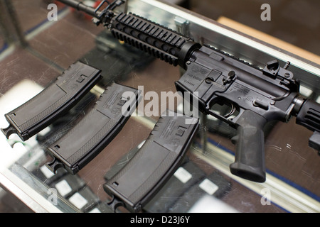 Ein Colt Defense M4A1 Karabiner Sturmgewehr auf dem Display auf ein Waffengeschäft mit hoher Kapazität 30 Runde Zeitschriften. Stockfoto