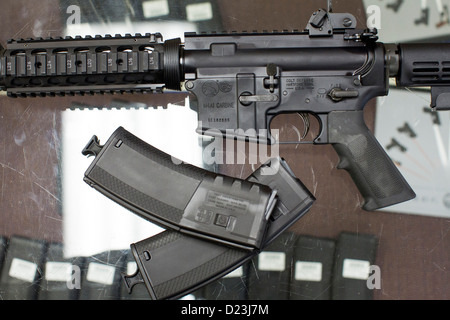 Ein Colt Defense M4A1 Karabiner Sturmgewehr auf dem Display auf ein Waffengeschäft mit hoher Kapazität 30 Runde Zeitschriften. Stockfoto