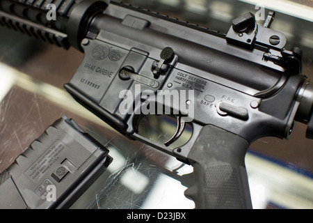 Ein Colt Defense M4A1 Karabiner Sturmgewehr auf dem Display auf ein Waffengeschäft mit hoher Kapazität 30 Runde Zeitschriften. Stockfoto