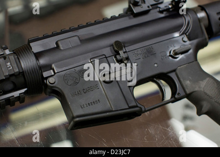 Ein Colt Defense M4A1 Karabiner Sturmgewehr auf dem Display auf ein Waffengeschäft mit hoher Kapazität 30 Runde Zeitschriften. Stockfoto