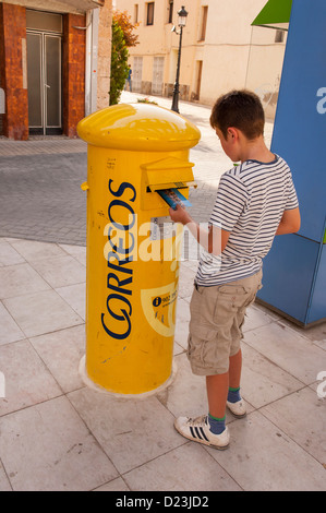 Ein 12 Jahre alter Junge Postkarten in einen Briefkasten in Spanien buchen Stockfoto