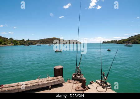 4 Angeln Straßen am Ende des Piers unbeaufsichtigt mit kleinen Fischerbooten im Hintergrund, Mangonui Harbour, New Zealand, Stockfoto