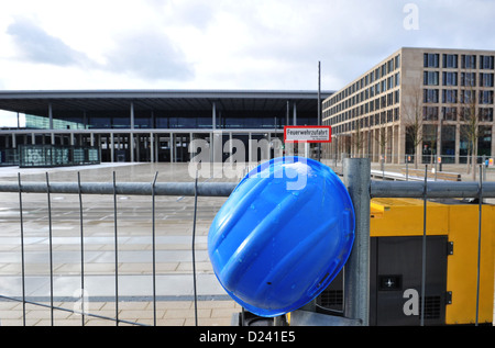 Ein Helm hängt an einem Bauzaun am Berlin Brandenburg Flughafen BER in Schönefeld, Deutschland, 11. Januar 2013. Nach weiteren Aufschub der Eröffnungstermin ist es unklar wann genau werden Flugzeuge starten und landen am Flughafen. Foto: PAUL ZINKEN Stockfoto