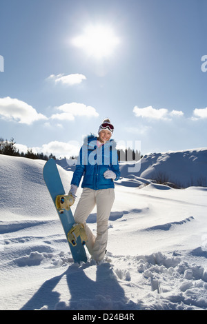 Hübsches junges Mädchen stehend mit Snowboard in ihrer Hand, sonnigen Wintertag Stockfoto