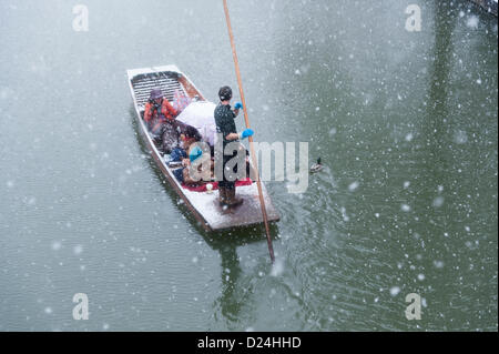 Cambridge UK 14. Januar 2013.  Touristen gehen auf dem Fluss Cam in starkem Schneefall Stechkahn fahren. Dicken Schnee fiel im Laufe des Nachmittags in East Anglia und Touristen genießen die Winterlandschaft auf dem Rücken von den pädagogischen Hochschulen trotz des Wetters. Sie geschützt unter Schirmen, während ihr Chauffeur Punt ihnen eine geführte Tour gab. Stockfoto