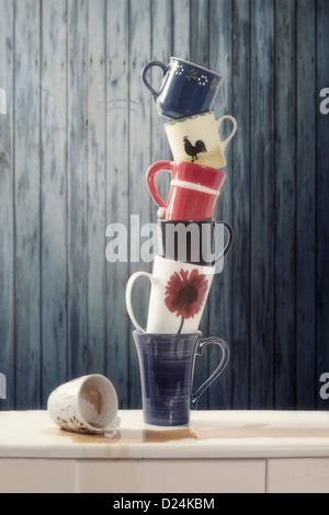 ein Stapel von ausgewogenen Tassen verschüttet eine Tasse Kaffee Stockfoto