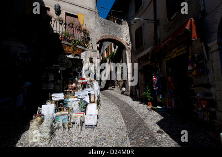 Eine schmale gepflasterte Straße mit Touristenläden unter der Straße Ein mittelalterlicher Torbogen in der mittelalterlichen Stadt Malcesine On Das Ostufer des Gardasees Stockfoto