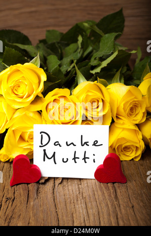 Gelbe Rosen mit zwei roten Holzherzen und eine Karte mit den Worten "Danke Mutti" Stockfoto
