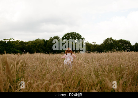 Ein kleines Mädchen zu Fuß in ein Feld, hintere Ansicht Stockfoto