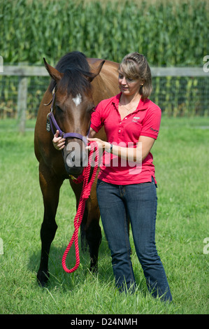 Weibliche Pferdesport Ausbilder und Reiter mit einem Pferd vor Pferdeställe stehend Stockfoto