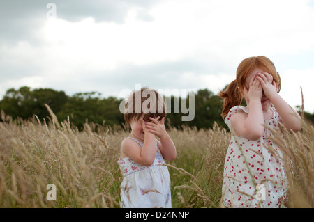 Zwei Mädchen spielen verstecken und suchen in einem Feld Stockfoto