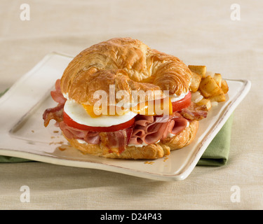 Frühstücks-Croissant-Sandwich mit Eiern, Speck, Schinken und Käse Stockfoto