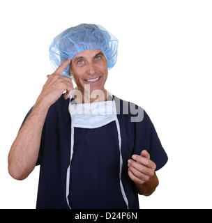 Lächelnd Chirurg tragen dunkelblaue Peelings, Haar Abdeckung und Maske hängen nach unten, auf sich selbst gerichtet Stockfoto